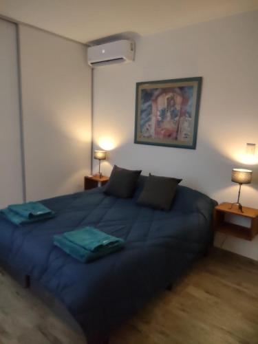 a blue bed in a room with two lamps at Departamento Alquiler Temporal en Chascomús in Chascomús