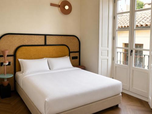 a bedroom with a white bed and a window at Hotel Casa Beatas in Málaga