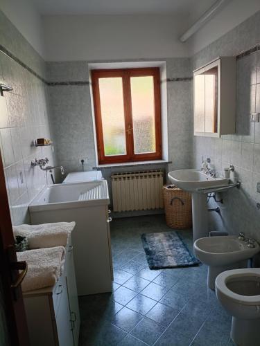 ein Badezimmer mit zwei Waschbecken, einer Badewanne und einer Toilette in der Unterkunft Ca' Susy in Samone