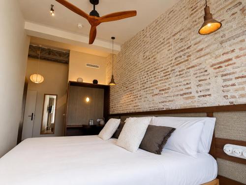a bedroom with a white bed with a brick wall at Cosy Rooms Bolsería in Valencia