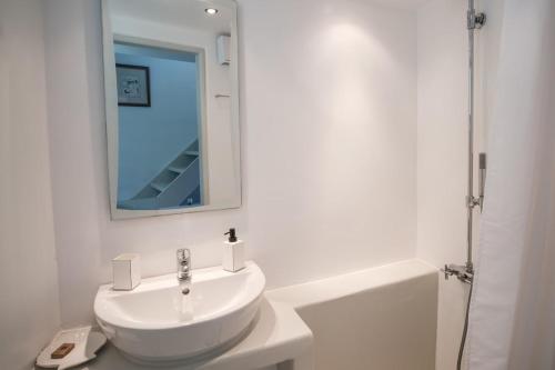 a white bathroom with a sink and a mirror at The Ioulis Pool in Ioulis