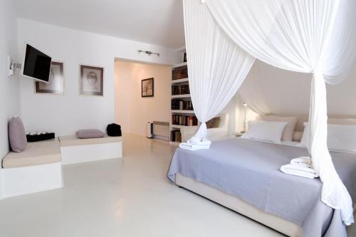 a white bedroom with a bed with a canopy at The Ioulis Pool in Ioulis