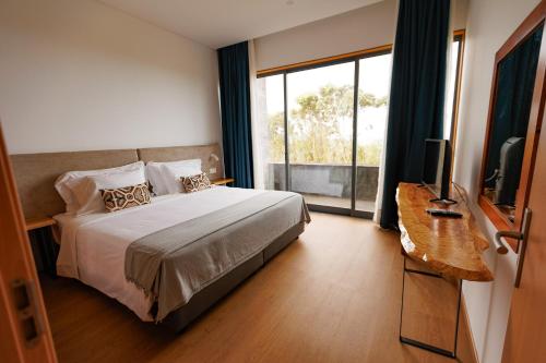 a bedroom with a bed and a large window at Hotel Colombo in Vila do Porto
