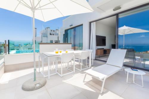 a balcony with white chairs and a table with an umbrella at Santa Barbara Residences by IDILIQ in Fuengirola