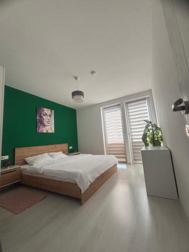 a bedroom with a bed and a green wall at Apartament Bella in Târgu-Mureş