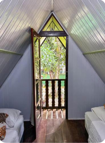 a small attic room with a window and a door at Chale do Índio - Ilha Grande in Angra dos Reis