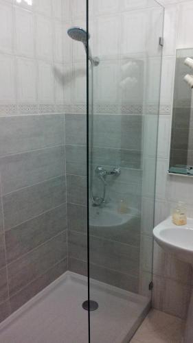 a shower with a glass door next to a sink at Apartamento Tavira in Tavira