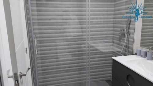 a shower with a glass door next to a sink at ESTUDIOS CHINASOL - Bernardo Cózar in Almuñécar