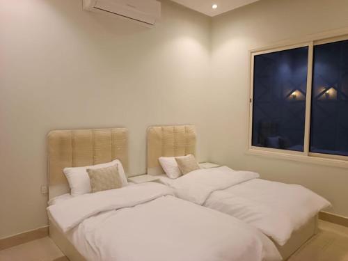 a room with two beds with white sheets and a window at روشيلا in Al Majma'ah