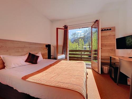 a bedroom with a bed and a desk and a television at Hôtel Lacour in Eygliers