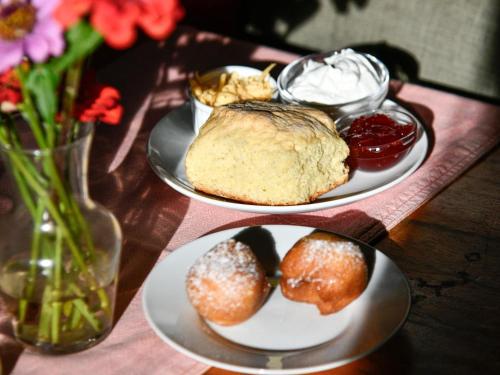 two plates of pastries on a wooden table with flowers at Mount Park Guest Farm in Dargle