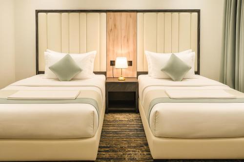 a hotel room with two beds and a table with a lamp at لحظات للشقق المخدومة in Jeddah