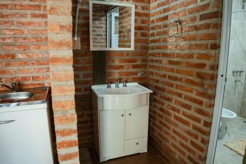 a bathroom with a white sink and a brick wall at Hotel alamos de la puntilla in Belén
