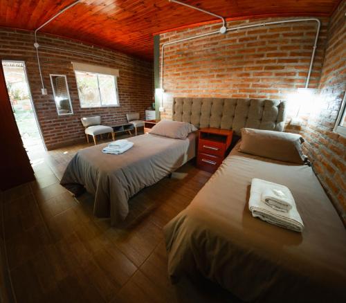 a bedroom with two beds and a brick wall at Hotel alamos de la puntilla in Belén