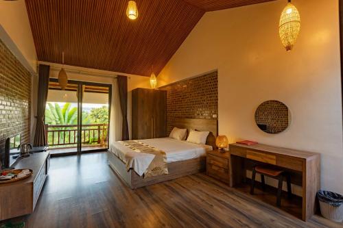 a bedroom with a bed and a desk and a window at Nan House - Tam Coc in Ninh Binh