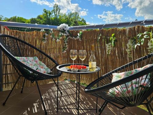 a patio with two chairs and a table with wine glasses at SilvaBlau Apartment Hévíz in Hévíz