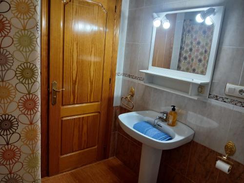 a bathroom with a sink and a mirror and a door at Casa rural el cerrete in Riópar