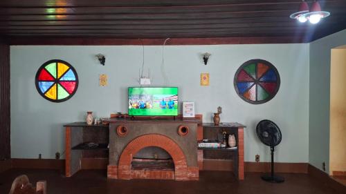 a living room with a tv and a fireplace at Moka Refúgium-Casa de praia aconchegante e espaçosa in Belém