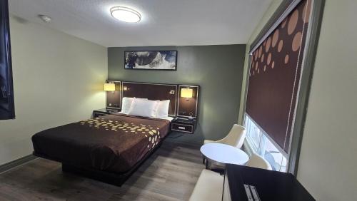 a small hotel room with a bed and a table at Knights Inn Bracebridge in Bracebridge