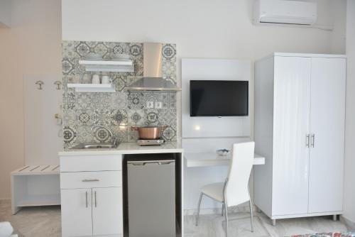 a kitchen with white cabinets and a tv on a wall at Ilion Luxury Studios & Apartments in Asprovalta