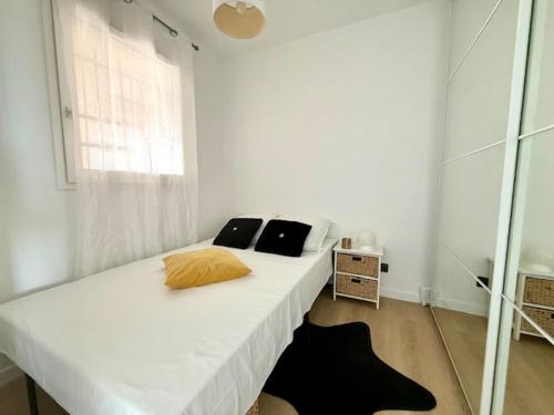 a bedroom with a white bed with two pillows on it at Le TAHITI in Frontignan