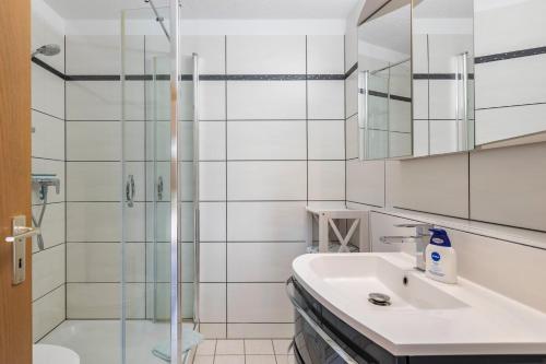 ein weißes Badezimmer mit Waschbecken und Dusche in der Unterkunft Seeperle in Moos