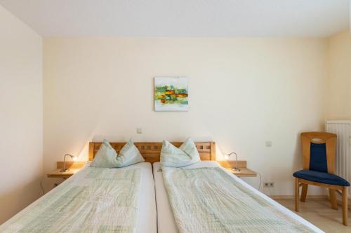 zwei Betten in einem Schlafzimmer mit einem blauen Stuhl in der Unterkunft Seeperle in Moos