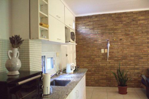 a kitchen with a sink and a brick wall at A bright, centrally located apartment in Barraquero