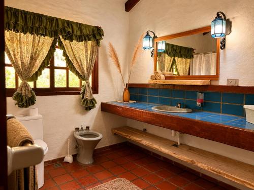 a bathroom with a toilet and a sink and a mirror at Valle Verde Lodge - Vista in Samaipata