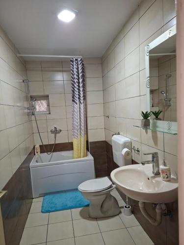 a bathroom with a toilet and a sink and a tub at Guest House Olbina in Korenica