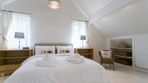 a bedroom with a white bed with towels on it at Brendon in Nefyn