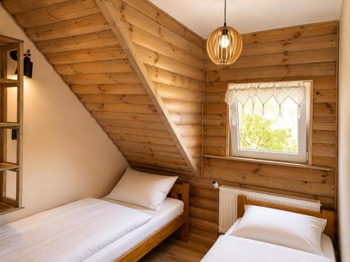 two beds in a room with wooden walls at Latarnia Wagabundy Bieszczady in Wola Michowa