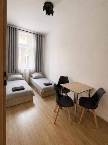 a room with two beds and a table and chairs at Apartamenty na Witosa in Nowa Sól