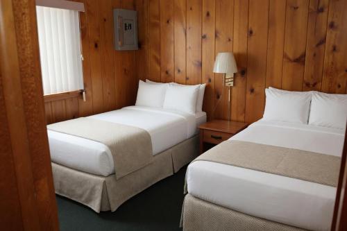 zwei Betten in einem Zimmer mit Holzwänden in der Unterkunft Paddle Inn in Ely