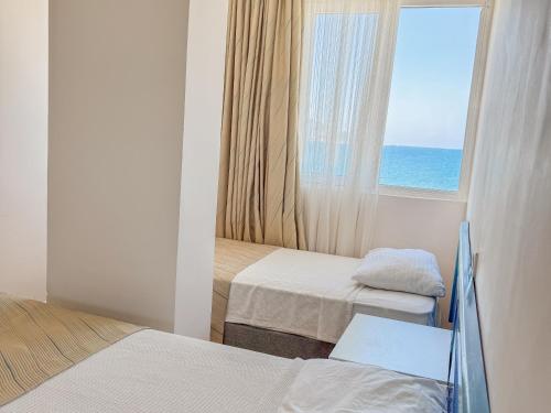 a room with two beds and a window with the ocean at Er-öz Hotel & Restaurant in Fethiye