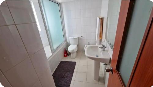 a white bathroom with a sink and a toilet at Espaço Acolhedor in Luanda