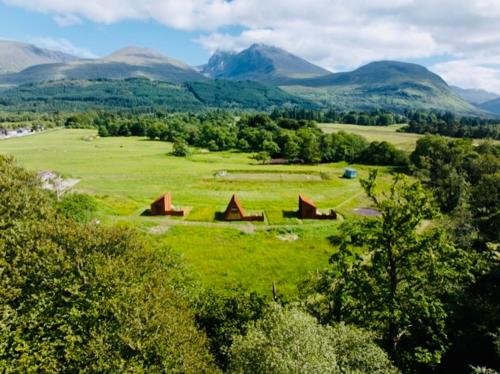 a green field with houses and mountains in the background at Ben Nevis Basecamp in Torlundy
