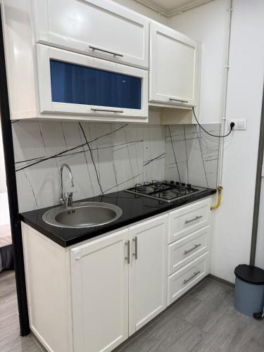 a white kitchen with a sink and a microwave at Casa Mare Oureah in Mazagran
