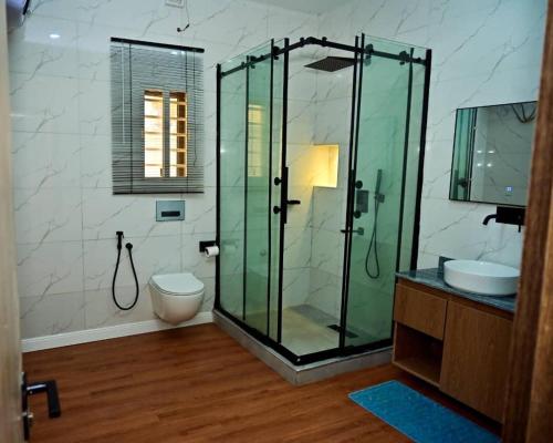a bathroom with a glass shower and a toilet at TM Homes in Abuja