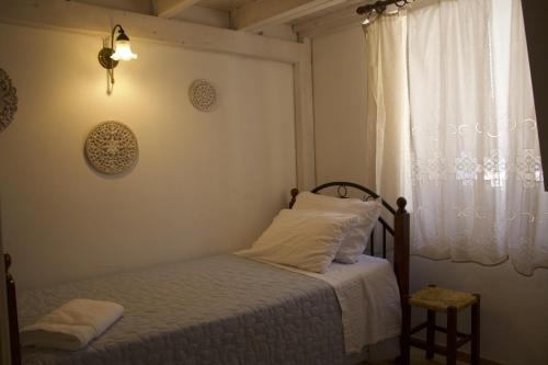a bedroom with a bed with white sheets and a window at Skalopetra in Pylos