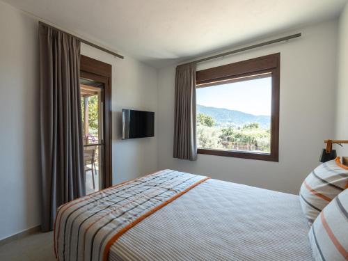 a bedroom with a bed and a large window at Elaionas Houses in Skala Potamias