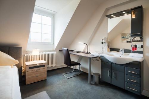 a bathroom with a sink and a desk with a mirror at Hotel Romäus in Villingen-Schwenningen