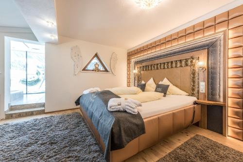a bedroom with a large bed with a wooden headboard at Hotel Schönruh in Gerlos