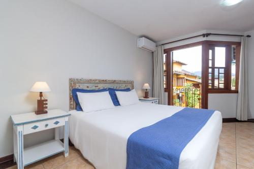 a bedroom with a large white bed and a window at Pousada das Pedras Paraty -RJ in Paraty