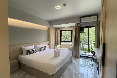 a bedroom with a large bed and a balcony at Baan Thanakul Suvarnabhumi in Ban Khlong Nong Pru