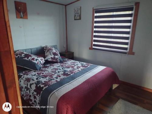 a bedroom with a bed with pillows and a window at Departamento con tinaja in Llanquihue