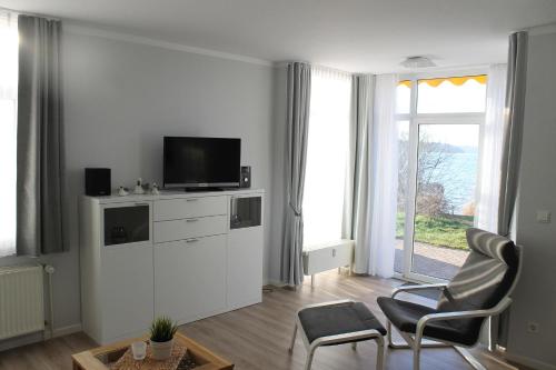 a living room with a tv on a white cabinet at Am Seeufer 59a Fewo 9 in Waren