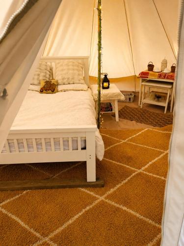 a bed in a tent in a room at Damson Keep Wild glamping pop up in Bere Alston
