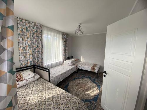 a room with two beds and a window and a door at Амир гостевой дом в Корумду in Korumdy