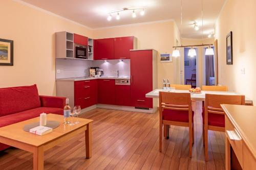a living room and kitchen with red cabinets and a table at Hafendomicil Appartement WH13 - Eisvogel in Waren